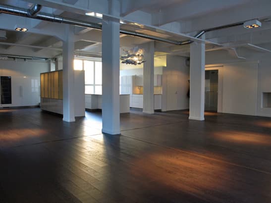 Open L22 hall with dark wood floors and white columns.