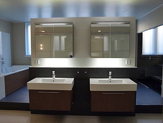 Twin vanity bathroom with mirrors, deep tones and indirect light.