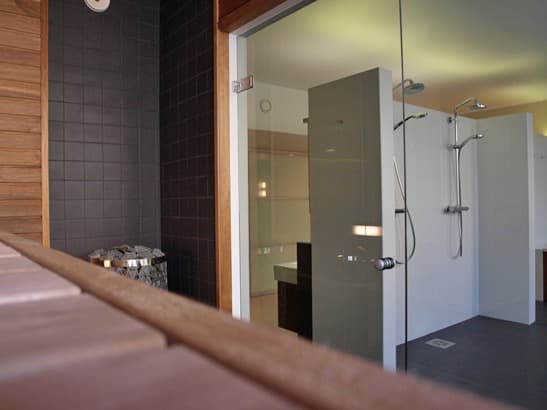 Sauna and spa area seen through glass with warm timber detail.